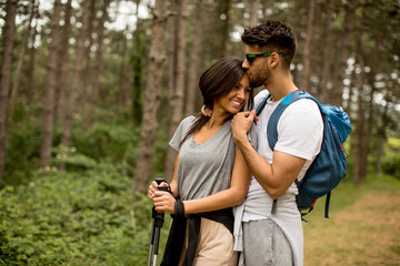 Smiling young couple walking with backpacks in the forest