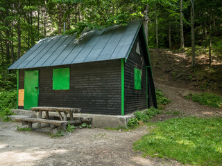 Small house with a wooden table and bench in the woods. Mountain shelter in the Bucegi mountains.