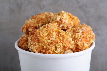 Bucket with yummy nuggets on blurred grey background, closeup