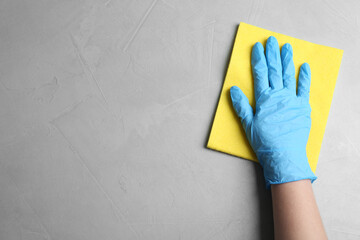 Woman in gloves wiping grey table with rag, top view. Space for text