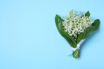 Beautiful lily of the valley flowers on light blue background, top view. Space for text
