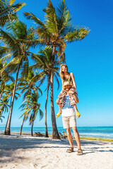 Man carries woman on shoulders on tropical beach in Zanzibar