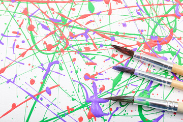 Brushes on canvas with colorful paint splashes, top view. Art and creativity