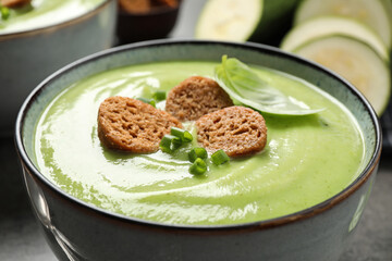 Tasty homemade zucchini cream soup in bowl, closeup