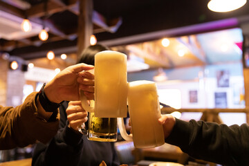 Group of hands holding a glass of fresh draft beer. Hand doing a beer toast at the party.