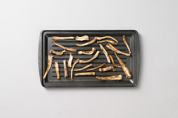 Healthly food. Dried chicory roots on a baking sheet. Light gray concrete background. Top view.