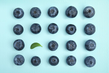 Fresh ripe blueberries and leaf on light blue background, flat lay