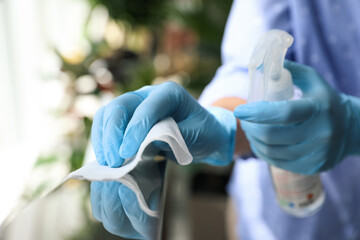 Woman in latex gloves cleaning railing with wet wipe and detergent indoors, closeup