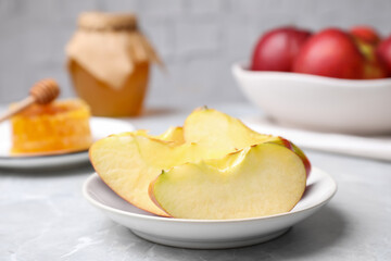 Apple slices near honey on light grey marble table, closeup. Rosh Hashanah holiday