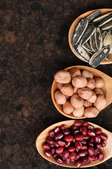 Assortment of beans and lentils in wooden spoon on teak wood background