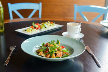 Salad with fresh grilled vegetables on a blue plate on black rustic wooden background.