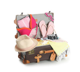 Open vintage suitcase with different beach objects packed for summer vacation isolated on white