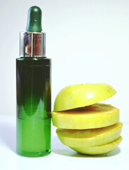 Green apple organic cosmetics for face anti-aging and refreshing treatment. Moisture gel hydration serum in a bottle and fresh apple in slices.