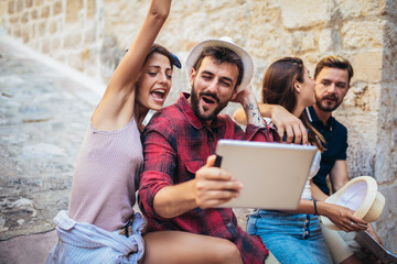 Happy friends enjoying sightseeing tour in the city, having fun, using digital tablet.