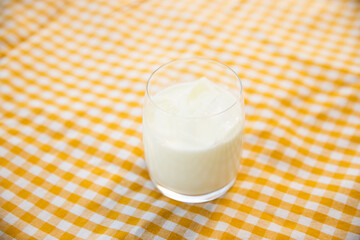 A glass of fresh milk with yellow stripe table cloth.