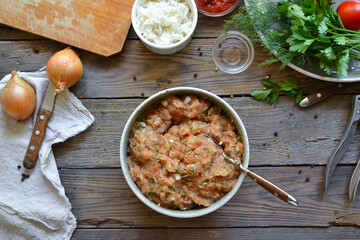 Chicken meatballs recipe. Step by step cooking meatballs in tomato sauce. Minced chicken in a bowl. Top view. Wooden background. Stir the minced meat