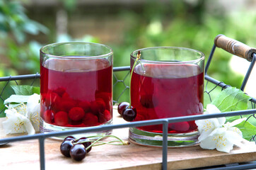 Fresh cherry juice on a wooden tray outdoor. Cherry compote