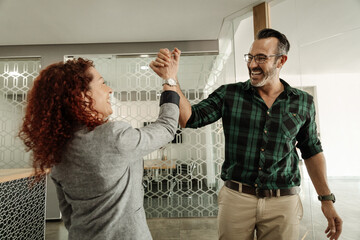 Two ecstatic businesspeople high-fiving together in an office