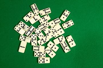 Close up of domino pieces with black dots in green table