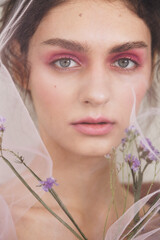 Beauty fashion portrait of young woman with flowers and tulle
