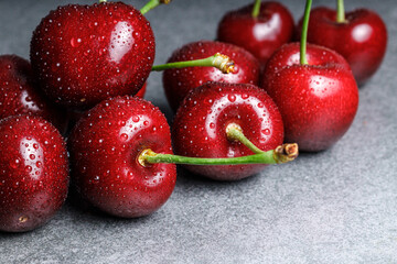group of dark red cherries laying in a row with fine water splashes on each cherry on light grey background, close up shot, soft reflections with moody soft shadows