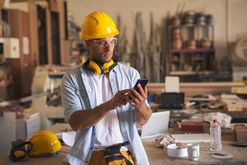 Young woodworker dialing phone number with a serious, frown look on his face