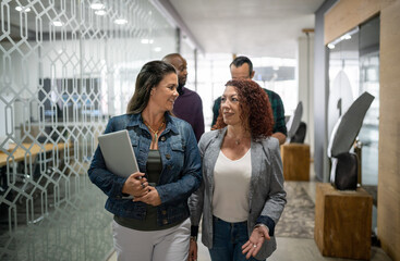 Smiling businesswoman talking together while walking down an office hallway