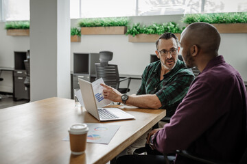 To diverse businessmen working together at an office table - Powered by Adobe