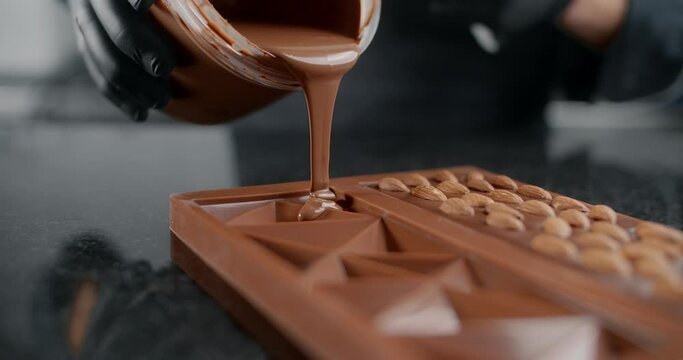 Chef confectioner makes chocolate bar - he pours hot melted chocolate to the silicone form, art of handmade chocolate, cooking desserts from chocolate and cocoa, making bars, 4k 120 fps Prores HQ