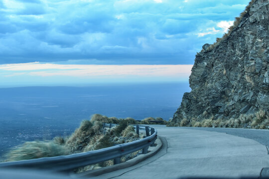 Carretera que baja junto a un precipicio con nubes de fondo