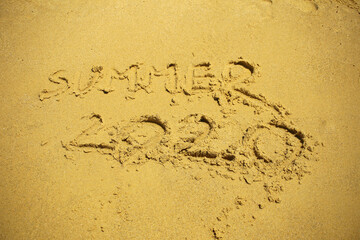 Summer 2020, written in golden sand, on the beach.