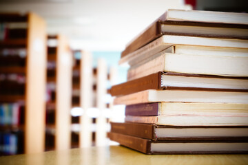 Stack of book on the  table with bookshelf.