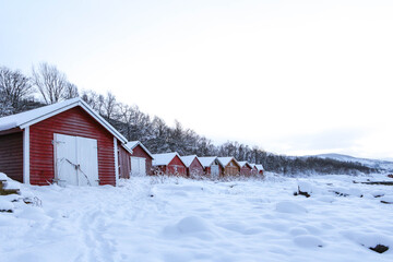 red typical houses in norway in winter. red wooden warehouses in scandinavia with white gates in the background of mountains