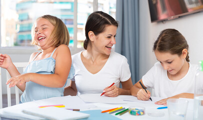 Obraz premium Mother and two children together with wax crayons in home