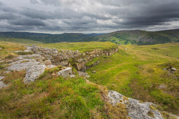 Fototapeta na wymiar Storm clouds over an abandoned quarry on the wild headland of Penwyllt with a view of Cribarth mountain which overlooks Abercrave in South Wales, UK, also known as The Sleeping Giant