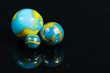 Blue and Yellow Colorful Marble Balls on Black background with reflection. Abstract Pattern