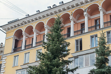Fototapeta premium A multi-storey building with columns and carved balconies on a cloudy summer day, in the Russian province. The architectural heritage of the USSR of the twentieth century.