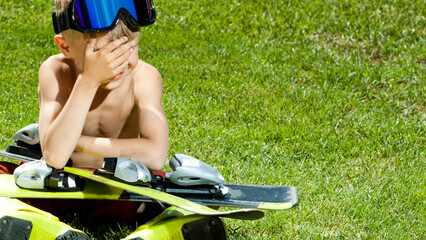  Funny little skier with ski on a green grass. Concept of active healthy lifestyle and waiting for...