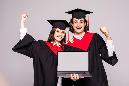 Young graduation couple holding laptop on white background