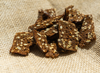 Fototapeta na wymiar dark rye crackers with seeds on sacking. Rustic style