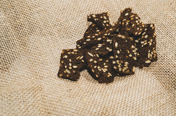 Plakat dark rye crackers with seeds on sacking. Rustic style. Healthy diet
