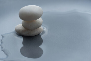 Fototapeta na wymiar white pebble rock pile on water on grey wellness and well-being health background