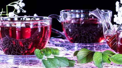 Hibiscus Red tea mug with carnation flowers close-up horizontal photo.English tea tradition.Medicinal therapy based on medicinal herbs and decoctions.Spicy herbs and medicinal broths.A relaxing drink