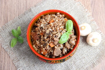 Buckwheat in merchant style with meat and mushrooms in the national wooden Russian dishes