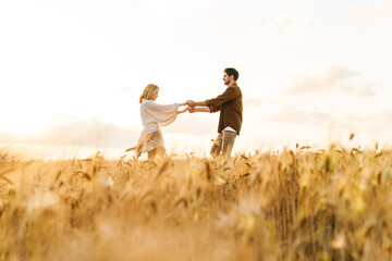 Image of young caucasian couple dancing in golden field on countryside