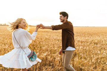 Image of young caucasian couple dancing in golden field on countryside