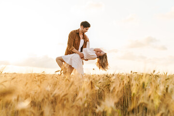 Image of young caucasian couple dancing in golden field on countryside