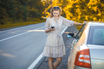 beautiful blonde talking on the phone near the car. breakdown on the road. road trip