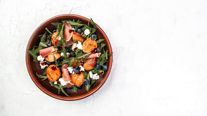 Gourmet salad with blue cheese, peaches, jamon ham and arugula on a light background, Flat lay. Banner. Top view