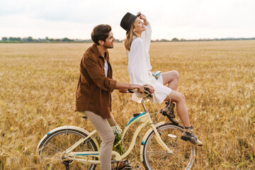 Image of young caucasian couple smiling and riding bicycle together